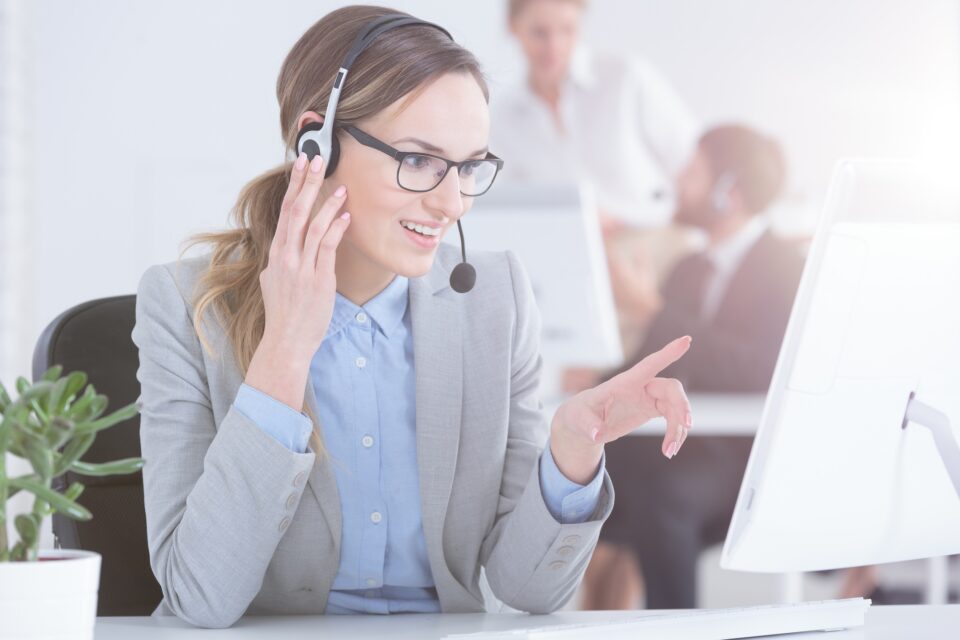 A cheerful answering service speaks to a caller over a headset for customer service spring cleaning blog.