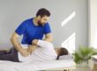 A professional chiropractor adjusts a man's back for why-your-chiropractic-office-needs-an-answering-service.